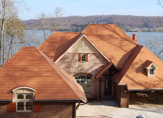 Brick home with a newly installed roof overlooking a lake—Cherry Roofing project showcasing residential new construction in the Pacific Northwest.