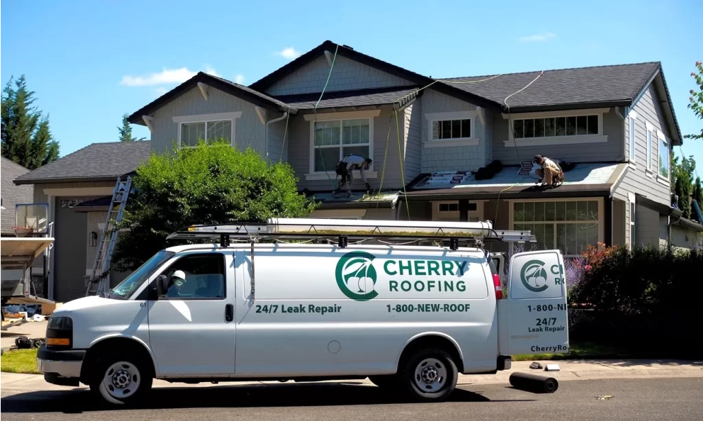 Cherry Roofing contractors installing a residential roof in Vancouver, WA, with branded service vans parked out front – a trusted local roofing company.